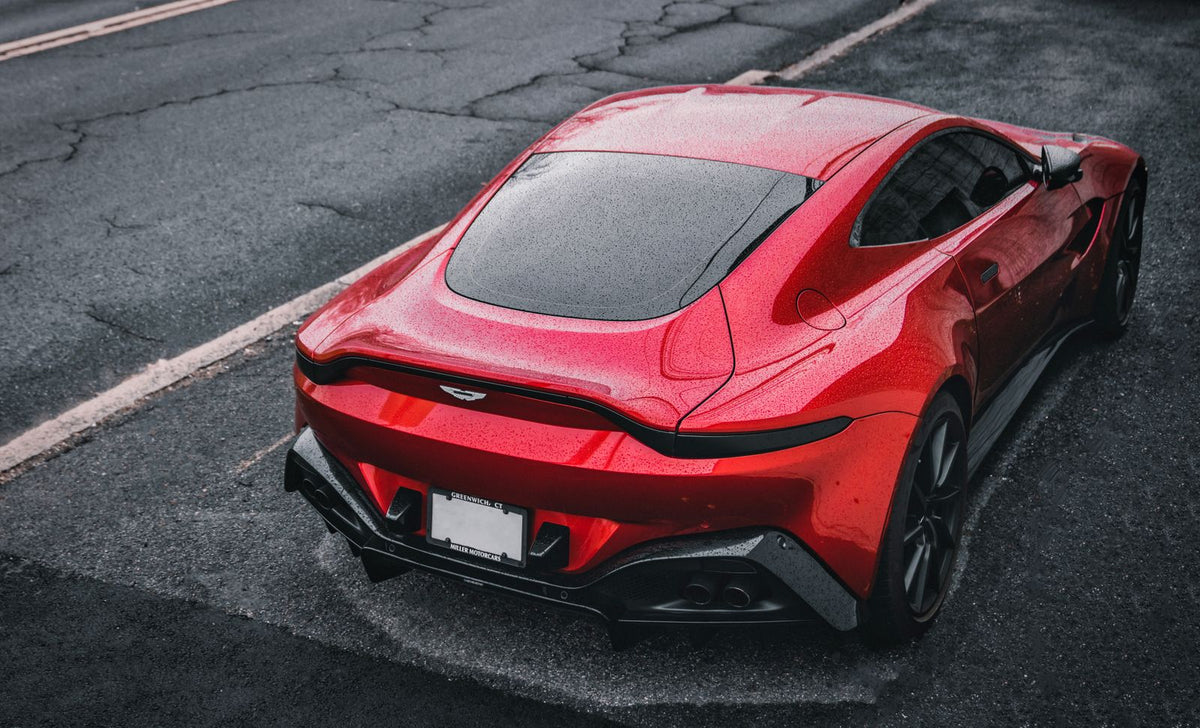 Red Aston Martin sports car on a wet city street