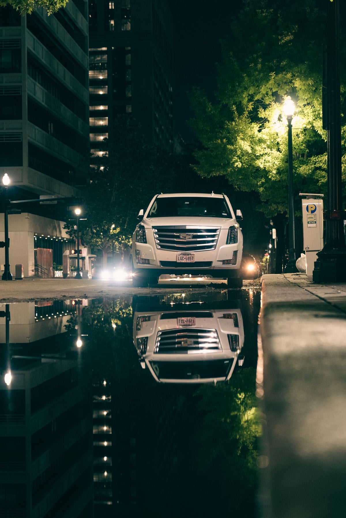 Cadillac Escalade parked by a puddle at night