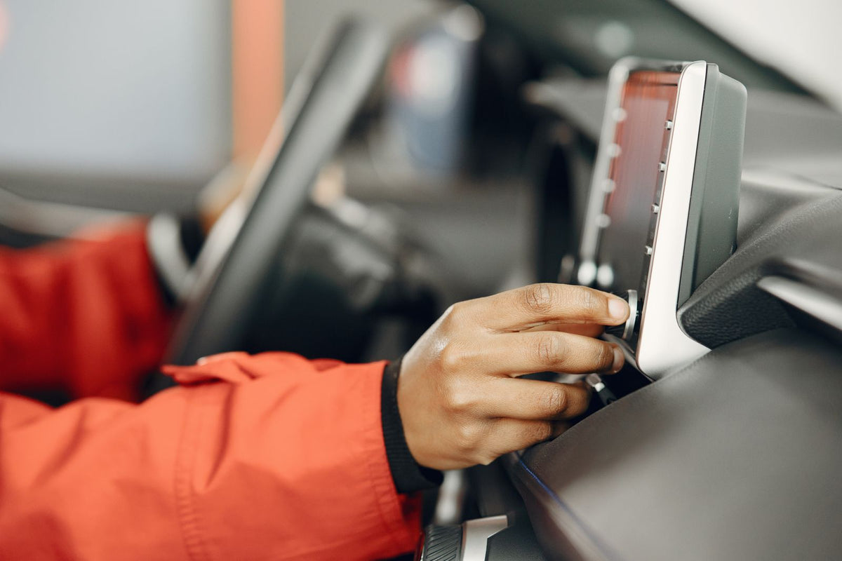 Driver adjusting a car stereo radio while driving